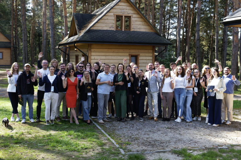 Grupa uczestników Zjazdu Szkoleniowego SMNS 2026 stojąca przed drewnianym budynkiem w Kowalówce.